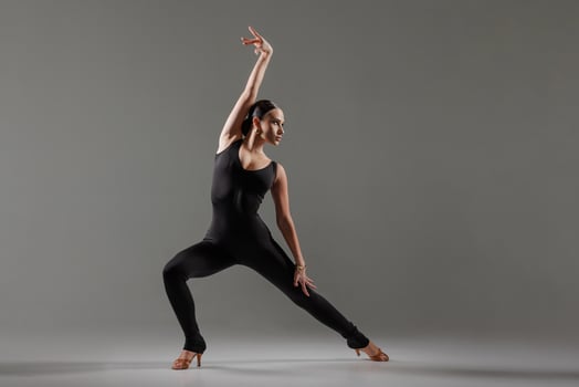 Dynamic dance solo. Woman dancing bachata on gradient yellow-orange background in neon light. Dance concept, lessons, school photo