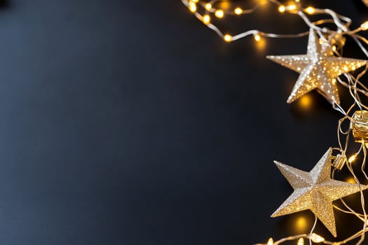 Festive decorations with glittering stars and fairy lights on a dark surface. photo