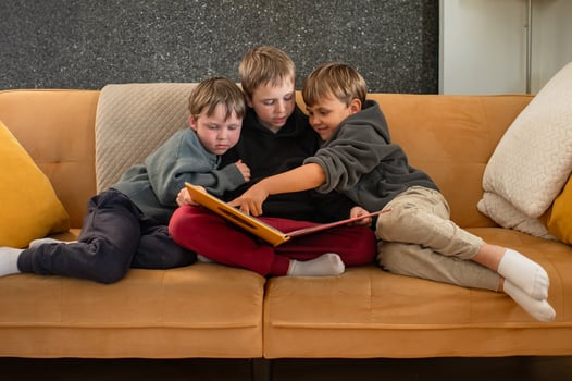 An older brother shares a story with his little siblings on the couch, as they listen with wide-eyed wonder. photo