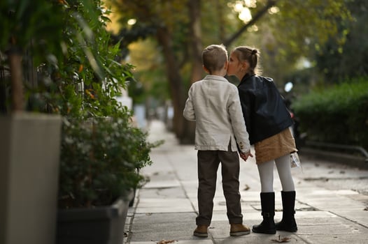 The girl kisses the boy on the cheek, both of them blushing and smiling sweetly. photo