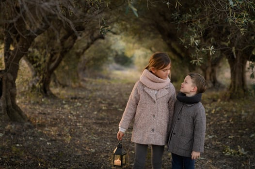 A fairytale-like moment as a brother and sister explore a glowing woodland path, lantern in hand. photo