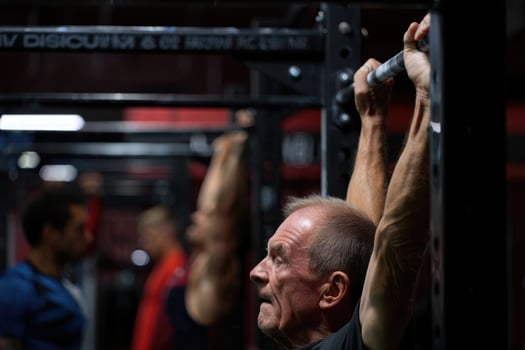 Senior man showcases his strength with determined pull-ups at the gym, embracing an active lifestyle. photo