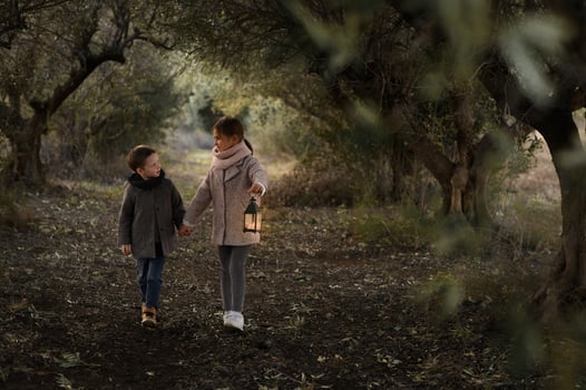 A magical tree tunnel frames two kids with a lantern, their faces glowing with curiosity and wonder. photo