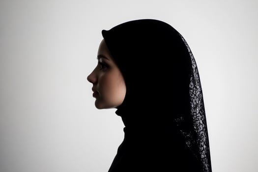 A silhouette of a woman in a hijab against a light background. photo