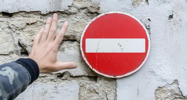 A hand reaching toward a red no-entry sign on a textured wall. photo