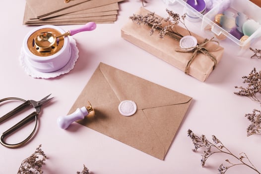 Craft envelope with wax seal and crafting items on pink photo