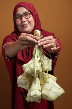 Muslim Woman Offering Ketupat for Eid Celebration photo