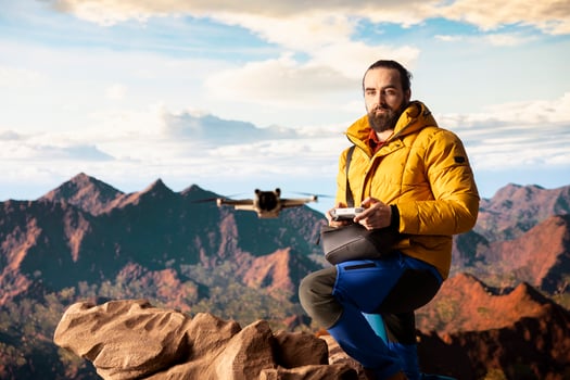 Male influencer shares hiking journey through vlog with drone, recording high quality aerial view content with remote control. Young hiker content creator filming scenery. photo