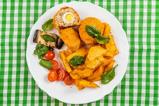 Delicious plate of fried food with vegetables on checkered tablecloth photo