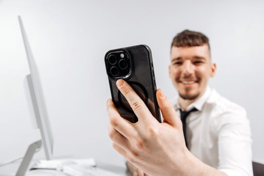 A business person receives a positive message on his phone while working at his computer. The concept of financial income, transaction. Banner, free copy space photo