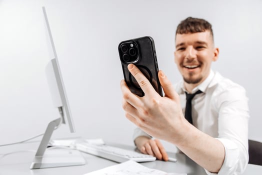 A business person receives a positive message on his phone while working at his computer. The concept of financial income, transaction photo