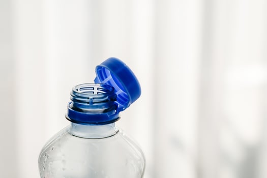 Close-up of a transparent PET bottle with a blue attached cap, designed for easy recycling. photo