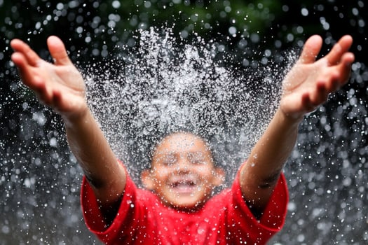 A young boy is splashing water on his face photo