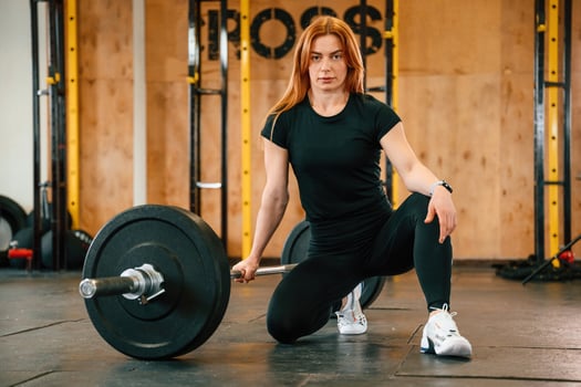 Front view. Sitting, barbell on the floor. .Beautiful ,strong woman is in the gym photo