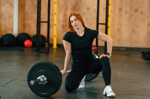 Sitting with barbell on the floor. .Beautiful, strong woman is in the gym photo