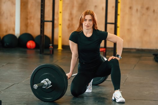 Sitting with ,barbell ,on the floor. Beautiful strong woman is in the gym photo
