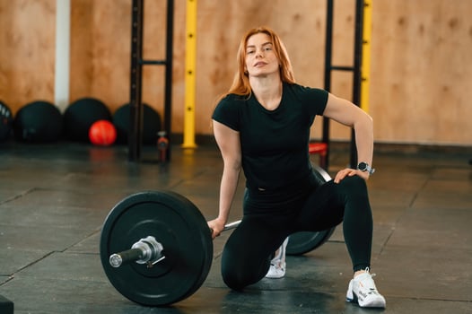 Sitting with barbell on the floor. Beautiful strong ,woman is in the gym photo