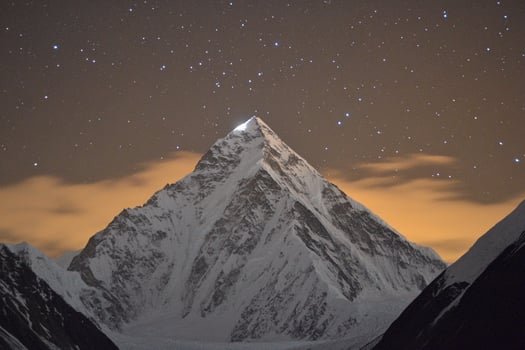 A mountain peak is lit up by the stars photo