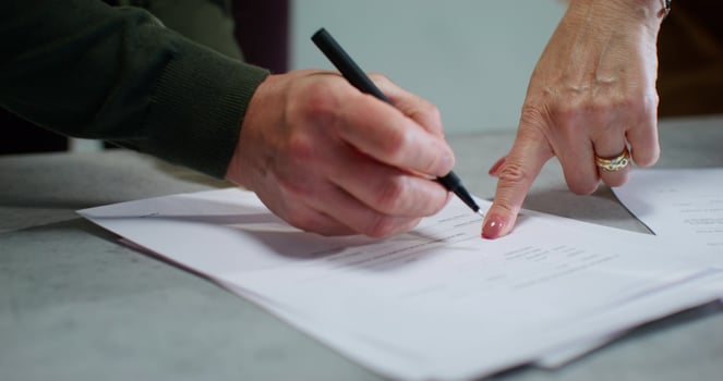 Buyers sign a real estate purchase and sale agreement with a realtor. Close-up of their hands, unrecognizable persons photo