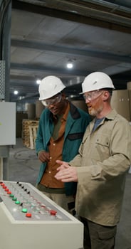 Paper factory interior showing two technicians in helmets and glasses standing by the equipment control panel. photo