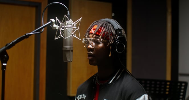 A stylish young man dances while recording rap in a studio photo