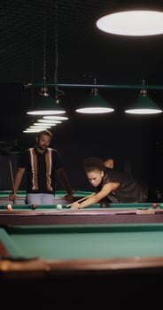 African-American woman is aiming and hitting ball with a cue, playing billiards photo
