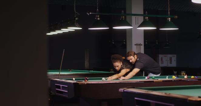 A young man explains and shows a young African American woman how to play billiards. Fun pastime with talking and playing photo