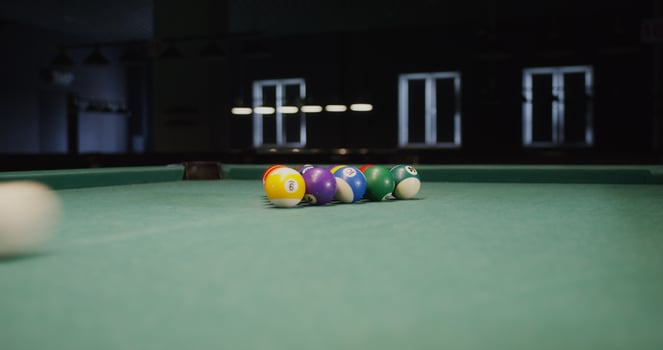 White billiard ball breaks a triangle of colored balls that fly to the sides, one ball flies into the hole, close-up, no people in the - triangle photo