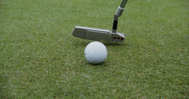 A golf club hits a ball, close up, no people. Details of playing golf on an artificial surface photo