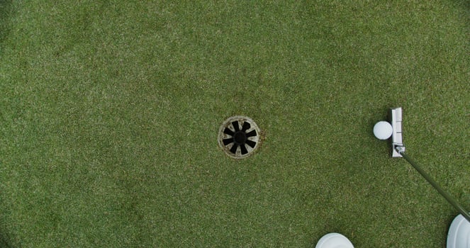 A man hits a ball with a golf club and it hits the target photo