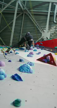 A woman athlete climbs up the climbing wall holding on to the artificial stones photo