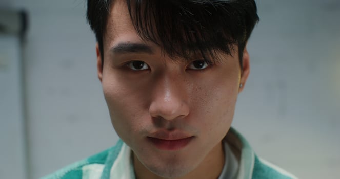 Close-up face of a young Asian man raising his eyes to the camera with a smile photo