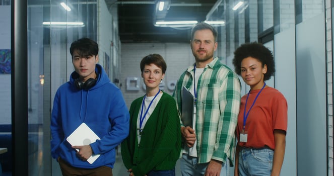 A group of young people standing in front of a glass wall photo