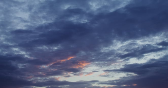 Dark cumulus obscures pink clouds illuminated by the setting sun photo