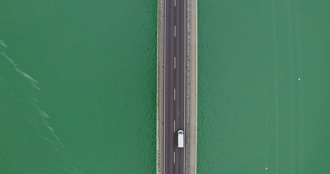 View from above, narrow road bridge with cars passing over it, over a river with green water with small ripples of waves. recording from a quadcopter photo