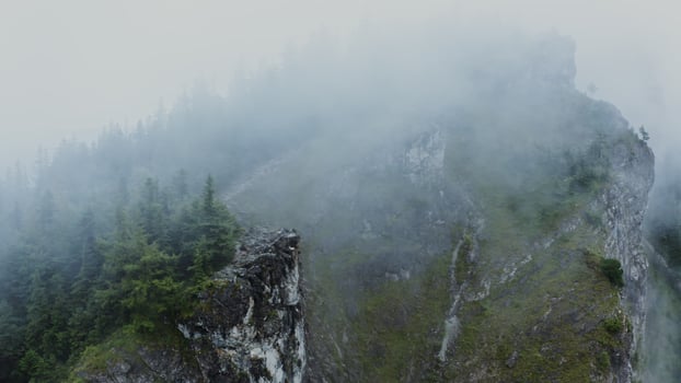 All round aerial from a drone, a view of the steep rocky mountains, overgrown with spruce forest and a small settlement at the foot of the mountain photo