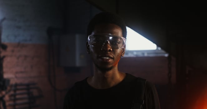 A man wearing glasses and a black shirt standing in front of a fire photo