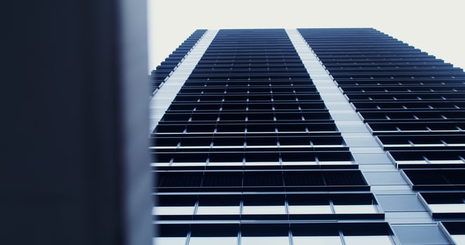 Facade of a high-rise office building with large panoramic windows. Business Quarter, no people on . The gray building of the business center. Skyscraper, view from below. photo