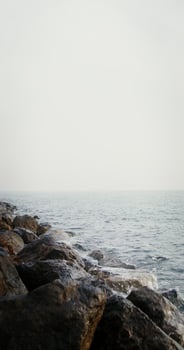 Sea waves hit large rocks on the coast, splashing and spraying in different directions. Vertical on a sunny day. 4k , red komodo photo
