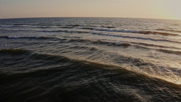 Panoramic view of the sea distance during dawn. Large foamy waves in the sun, from a drone. photo