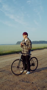 A young stylishly dressed man takes photographs with a camera while standing near a picturesque wheat field photo