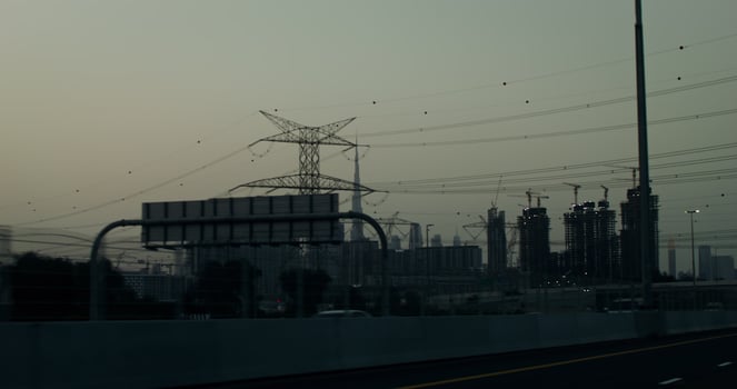 Busy highway on the outskirts of a modern metropolis with glass skyscrapers and many buildings under construction. Power lines above the road photo