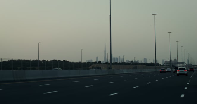 Busy highway on the outskirts of a modern metropolis with glass skyscrapers in the rays of the setting sun photo