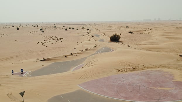The drone flies over a modern paved road with a roundabout covered with desert sands photo