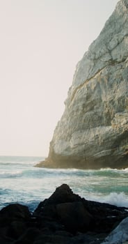 A cliff on the seashore, sea waves beating against a stone - against photo