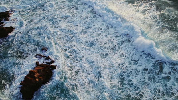 Top view of the foaming sea waves washing the coastal rocks, drone - foaming photo