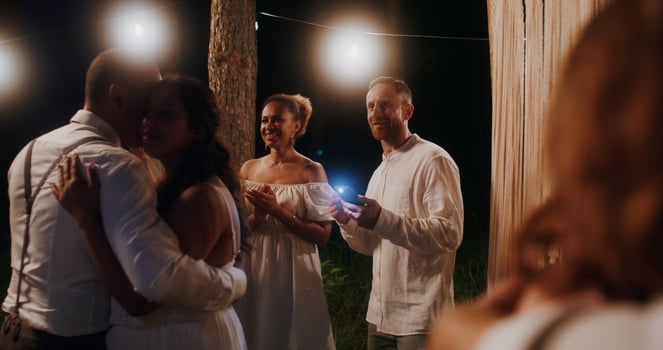 The bride and groom are dancing surrounded by their friends at an outdoor wedding feast at night - friends photo