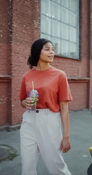 A young man and a woman smile, talk and drink lemonade while walking around the city. A man holds a longboard in his hands - lemonade photo