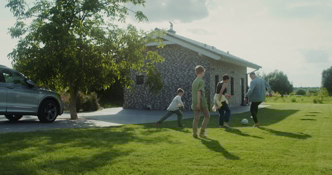 A man, a woman and two children play football in the backyard of their house, family outdoor leisure during vacation photo