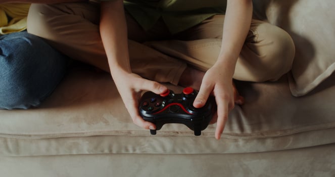 Mom and son of European appearance smile playing games using joysticks sitting on the couch in a stylish home interior photo